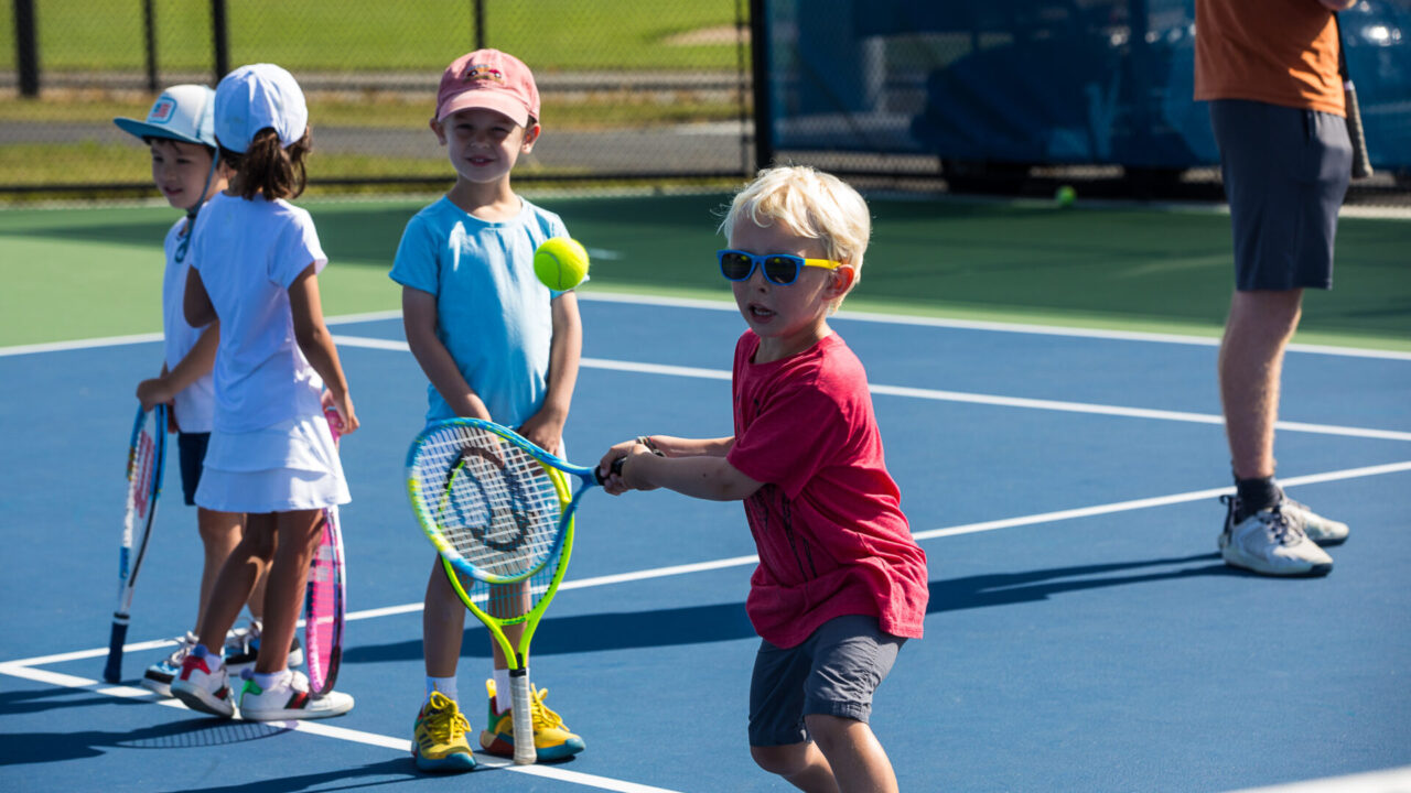 Group of children playing tennis.